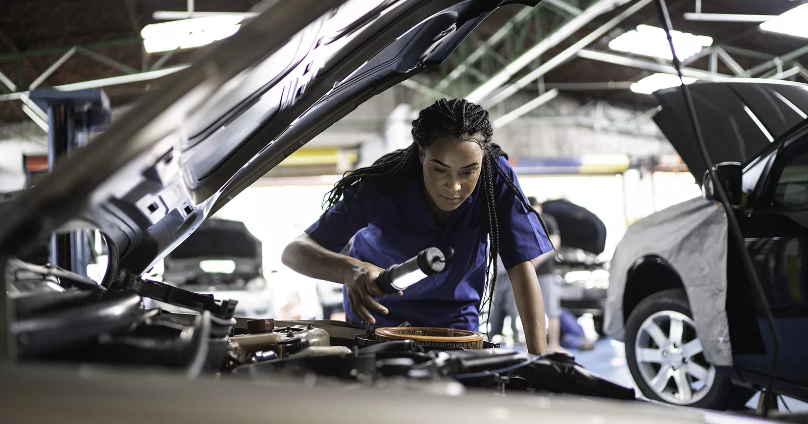 A mechanic under the hood of a car. Exponent materials engineers help improve automotive manufacturing and next-gen driving technology.