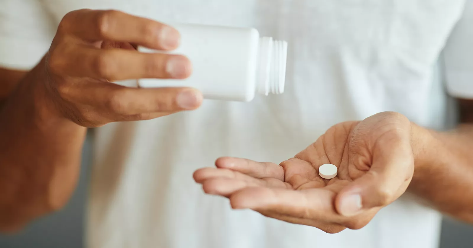 A person dispenses medicine from a bottle. Exponent helps improve the safety and efficacy of pharmaceutical products. 