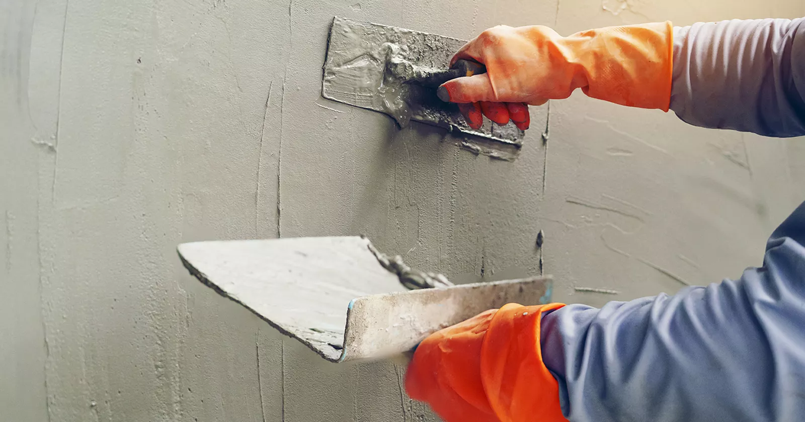 Worker applying stucco application to wall.  Exponent conducts  testing and analysis of construction products