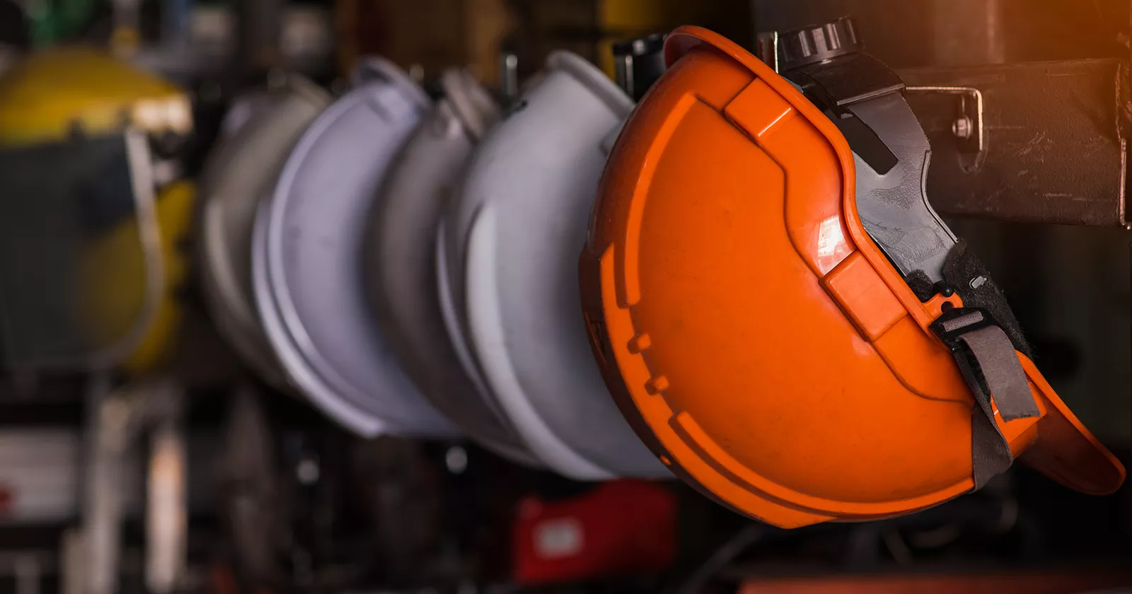 A row of orange industrial hard hats in a row. Exponent provides occupational and industrial workplace safety assessments