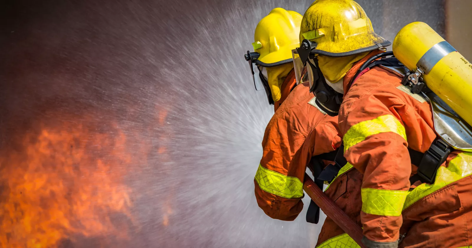 2 firefighters spraying high pressure water to fire