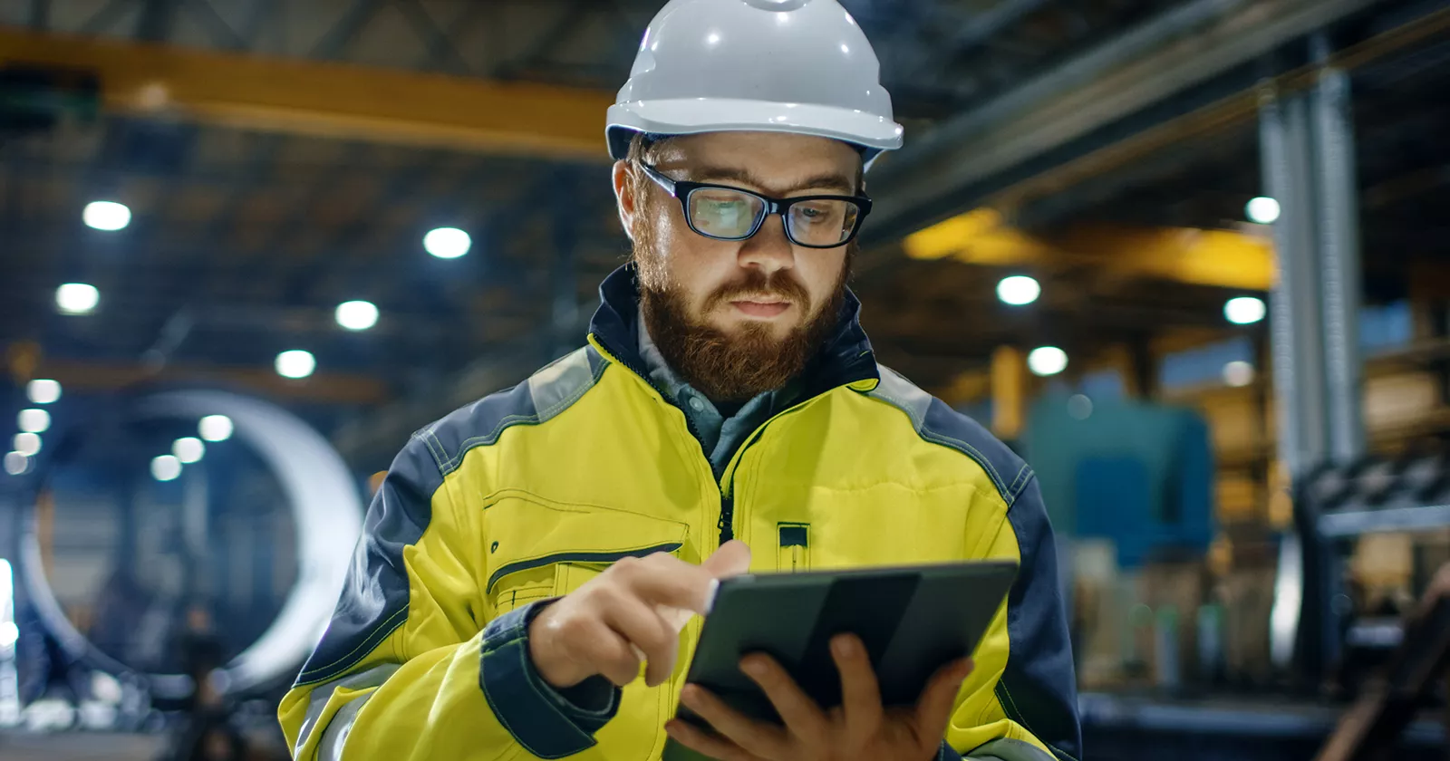 Inspector holds a clipboard and wears a hard hat in a factory setting. Exponent provides scientific and engineering risk assessments.