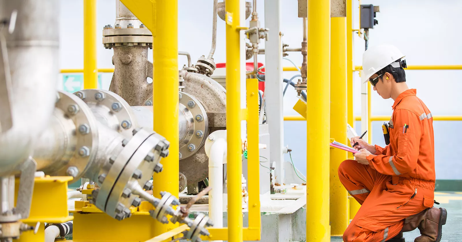 Worker in a factory setting examines a large pipe. Mechanical engineering expertise for all types of corrosion and materials challenges.