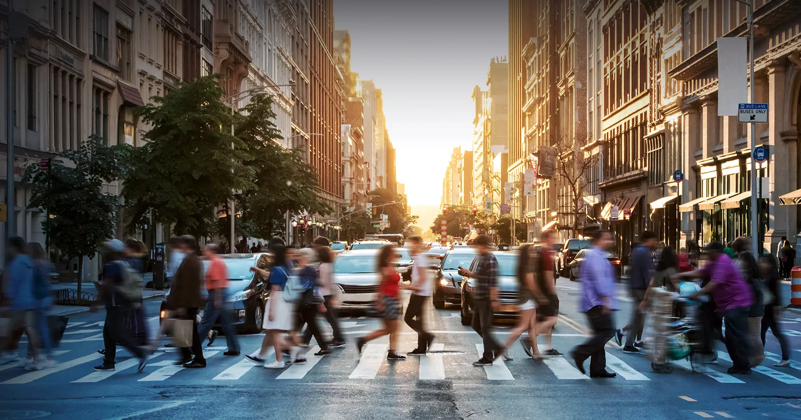 A crowd of people use a cross walk in a large city. Exponent helps build more inclusive technologies for all.