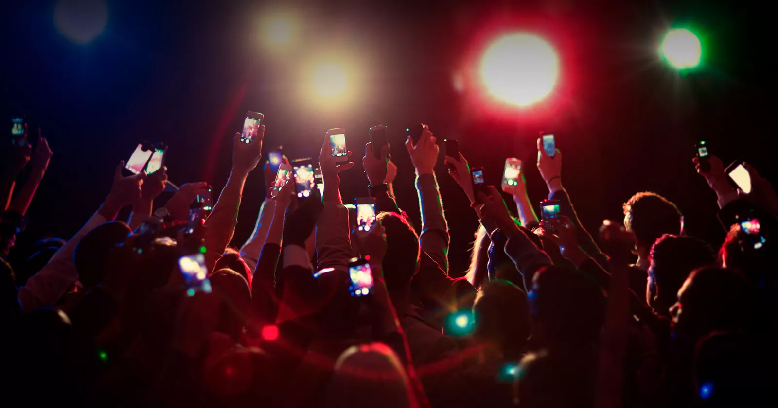 Crowd holds up cell phones at concert. Exponent provides technical engineering support for electronic device development.