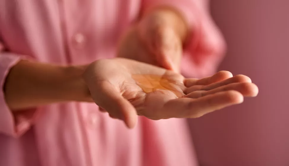 Close up of a hand with orange serum pooling in the middle of the palm