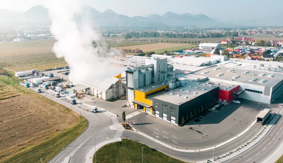 Aerial view of a manufacturing plant with smoke billowing from smokestacks