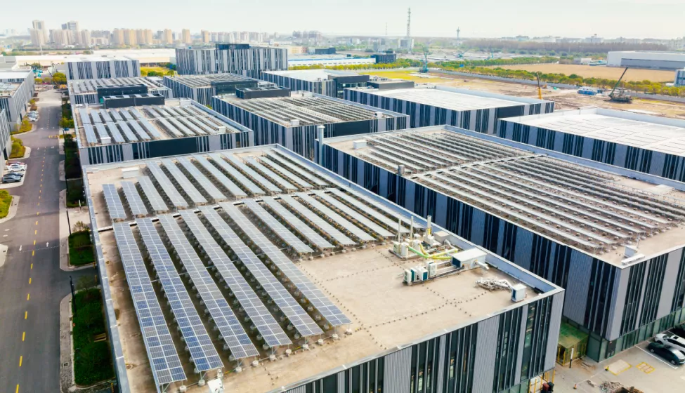 Aerial view of multiple office buildings all with solar panels covering the roofs, with a view of a downtown area in the distance