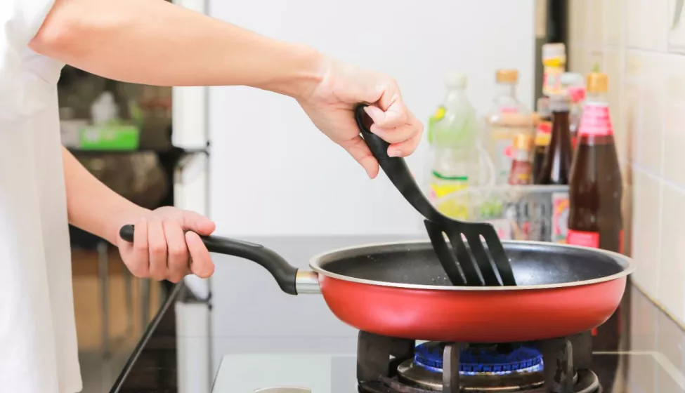 Cropped Hands Of Woman Frying Food In Kitchen