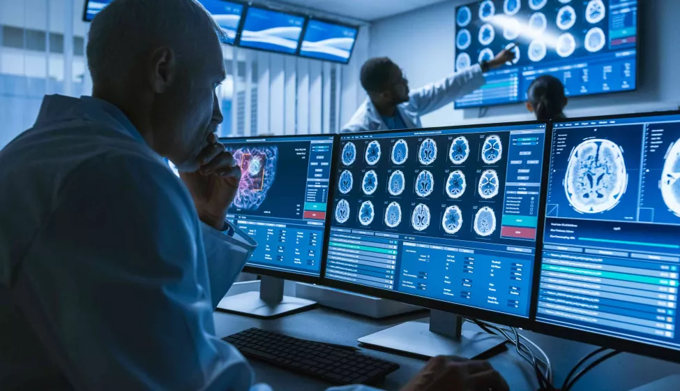 Person wearing a lab coat looks at screens in medical setting