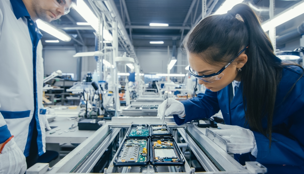 Electronics Factory Workers Assembling Circuit Boards by Hand While it Stands on the Assembly Line