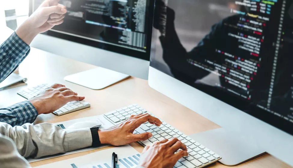 Hands typing on a keyboard while analyzing data on a computer screen. Exponent helps enhance the platforms and systems that drive business.