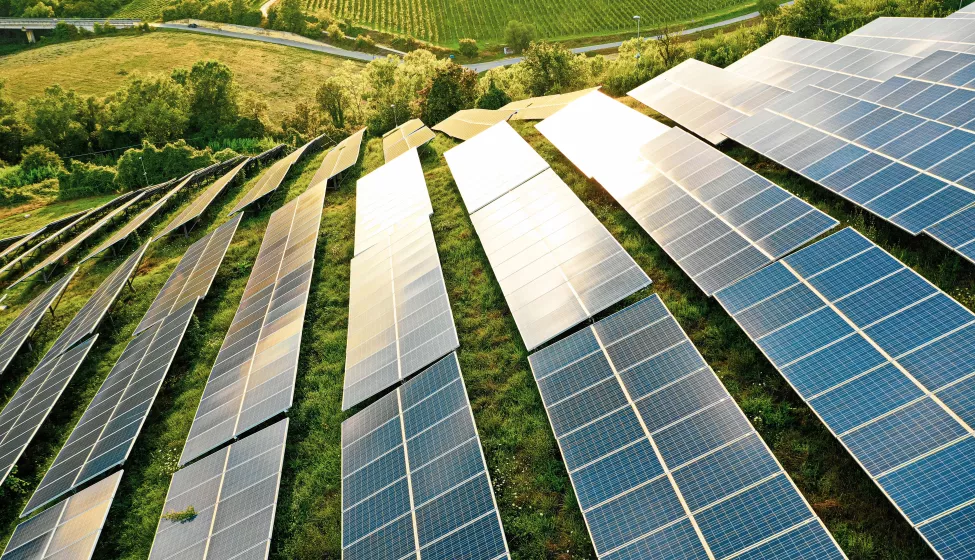 Multiple solar panels placed throughout a grassy field on a hill