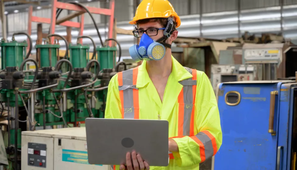 Caucasian male with protective mask with laptop working in factory area