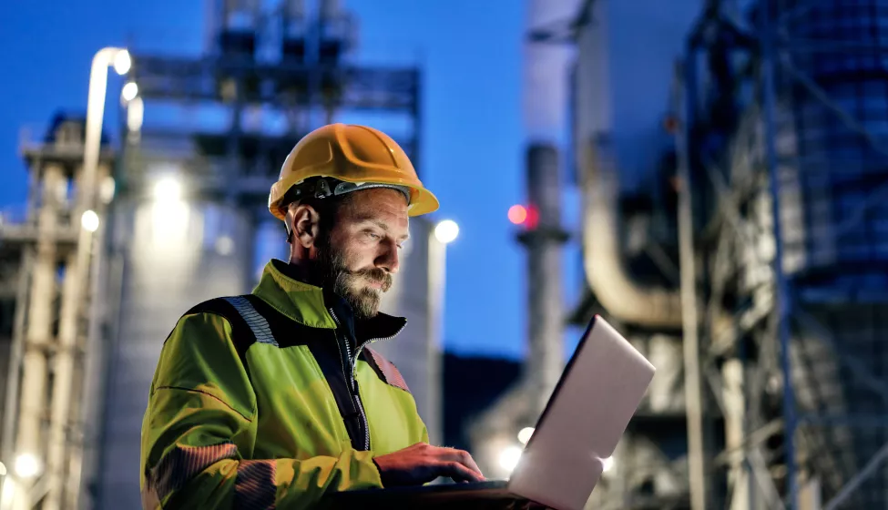 engineer wearing a helmet and using a laptop during his night shift