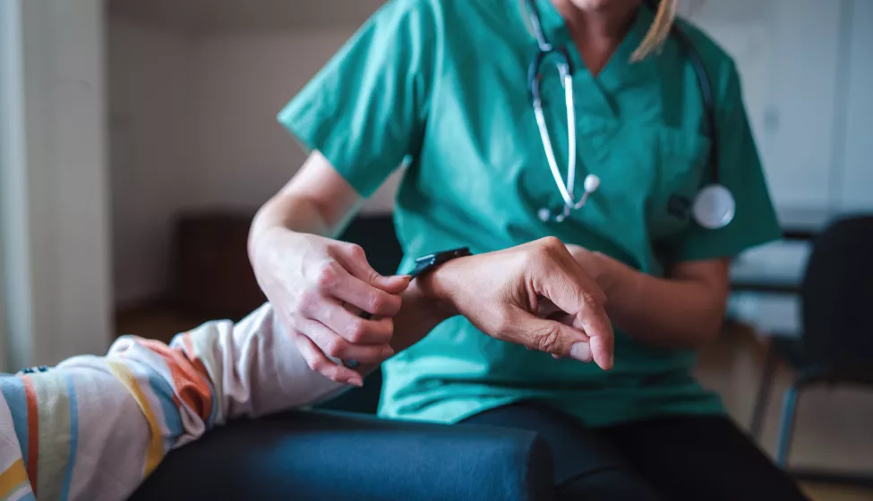 Smartwatch for health care. A woman from the medical health system wears a smartwatch for remote monitoring of vital signs on an elderly person