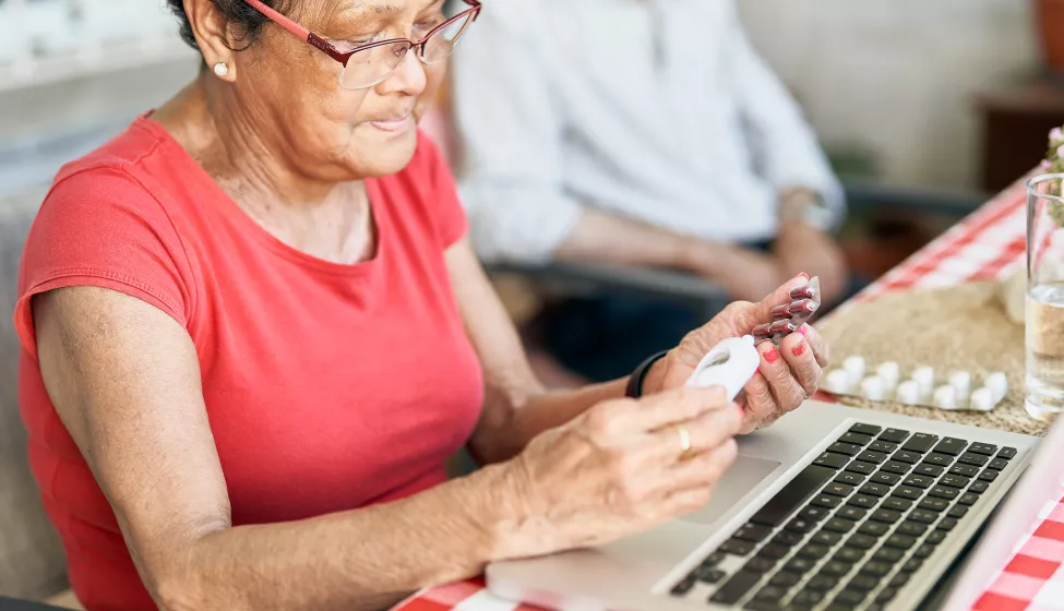 Patient looking over their prescriptions while sitting in front of a laptop