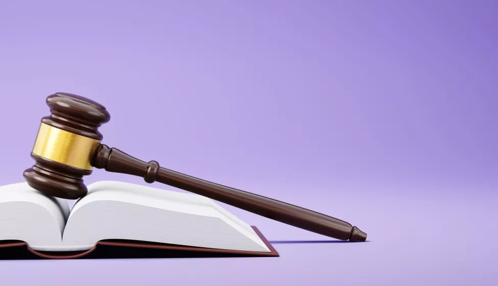 Judge's Gavel and an Open Book on Purple Background