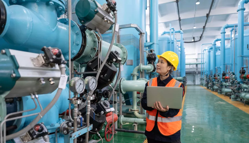 Female engineer works in a chemical plant using a laptop computer