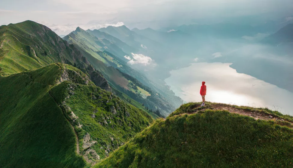 Aerial view of woman standing on top of the mountain ridge 