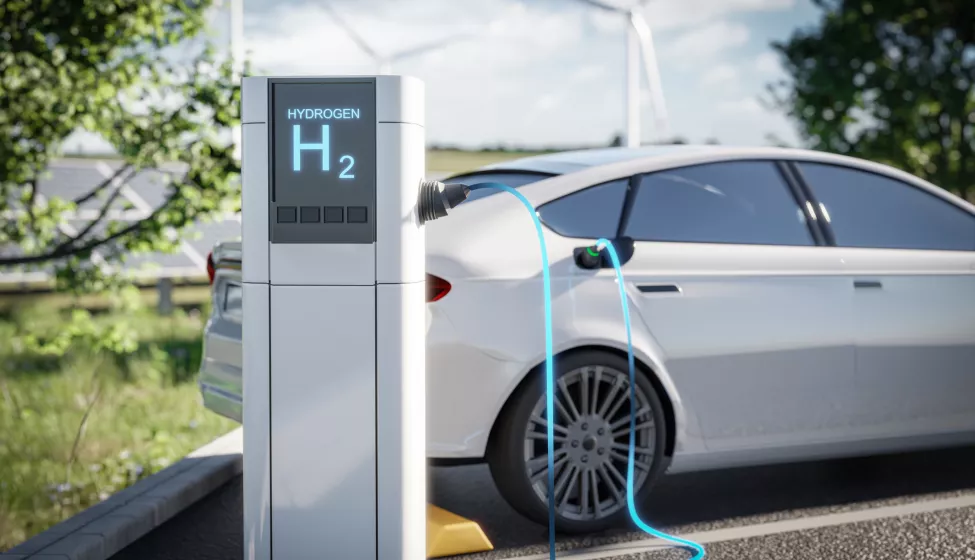 Electric car charging at a hydrogen station, set against a green environment with wind turbines in the background