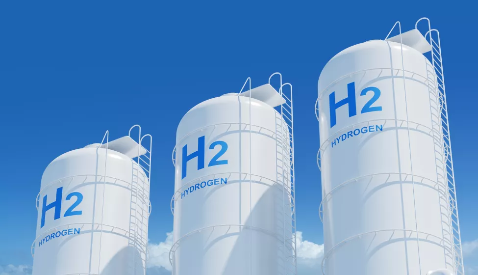 Large storage tanks with H2 and HYDROGEN labels on a blue sky background, representing hydrogen energy storage