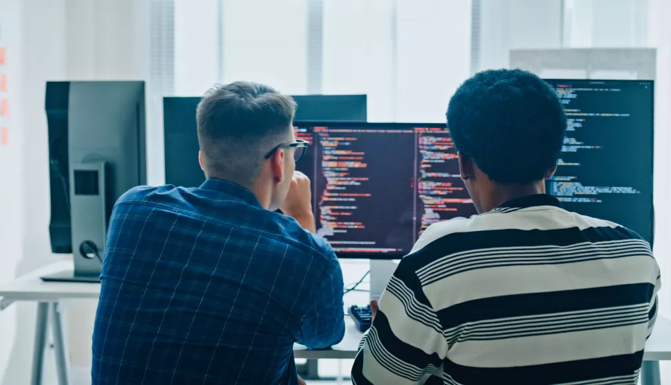 software developers meeting on multiple computer screens displaying programming code