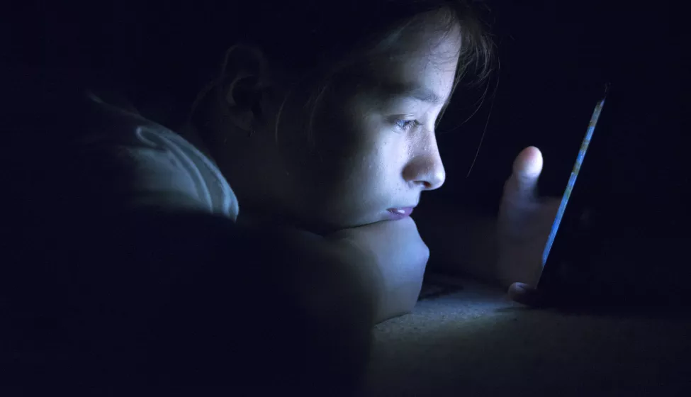 Kid using smart phone in a dark room