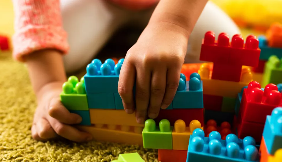 child playing with toy blocks on the carpet