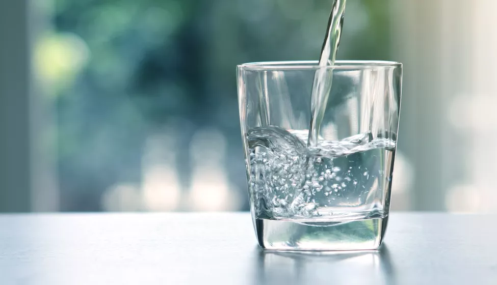 Close up the pouring purified fresh drink water from the bottle on table in living room 