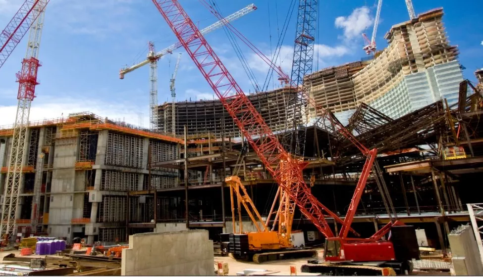 Two construction cranes on a large work site