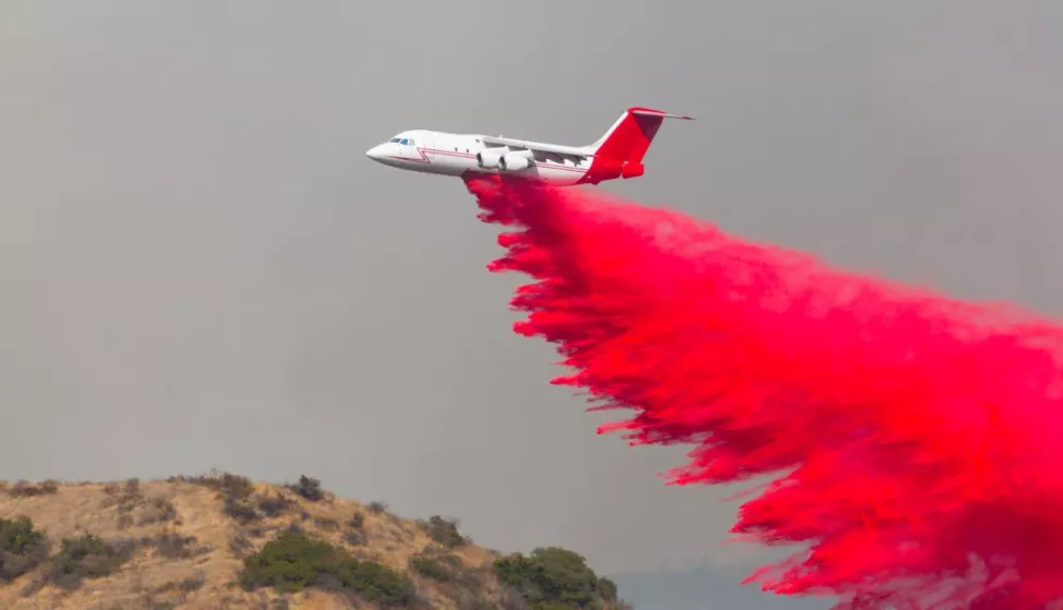 Pink fire retardant drops from a plane.