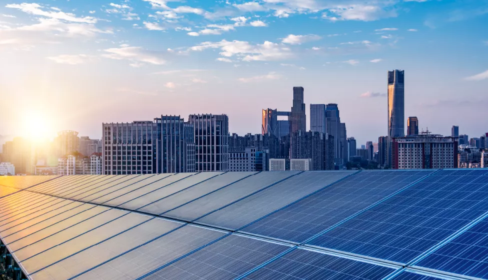 A closeup of solar panels with city high-rise buildings in the background