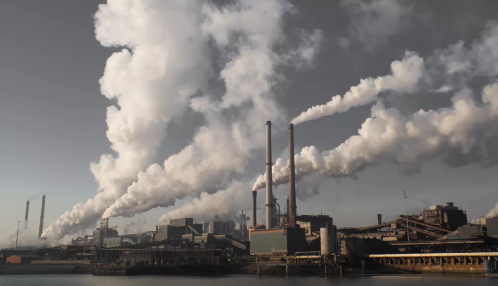 Smoke releases from several stacks at an industrial plant on a waterfront 