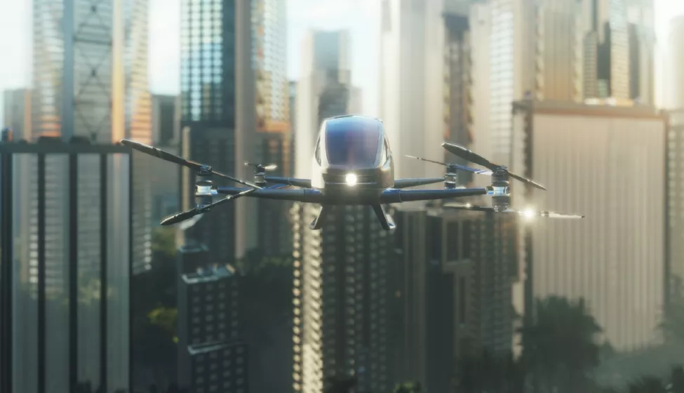 A black, futuristic-looking electric helicopter hovering over a city