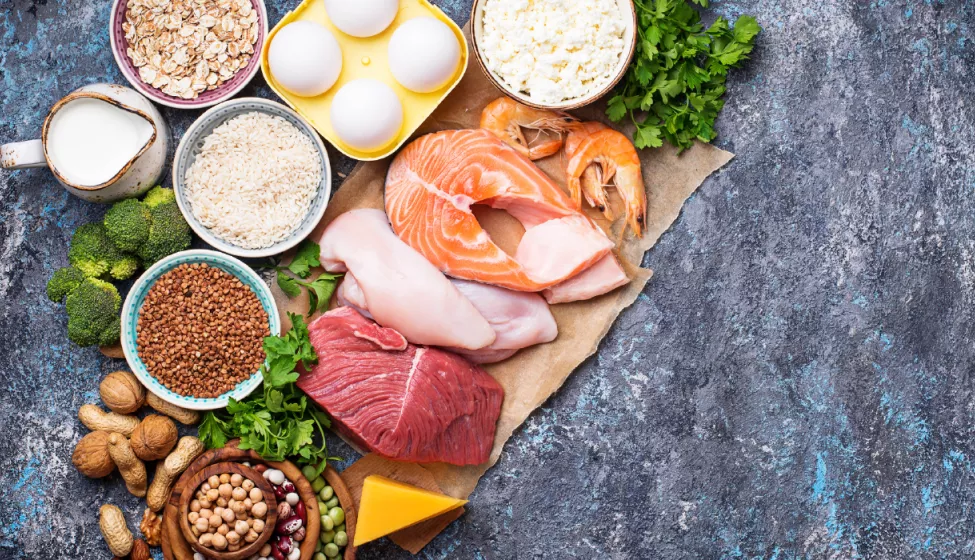 Carving board featuring an array of raw meat, vegetables, nuts, grains, and dairy foods