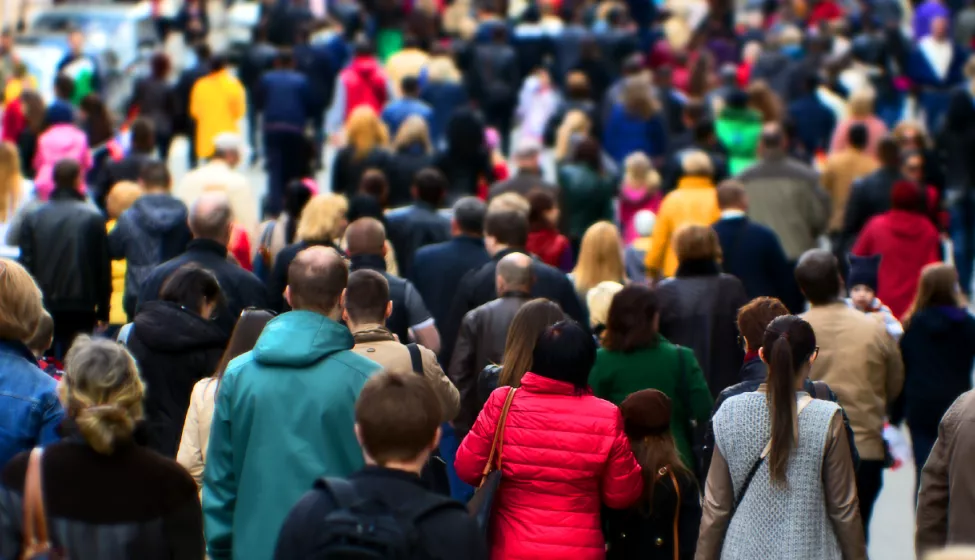 Crowd of people wearing coats and walking on sidewalk. Exponent conducts epidemiological and  biostatistical research.