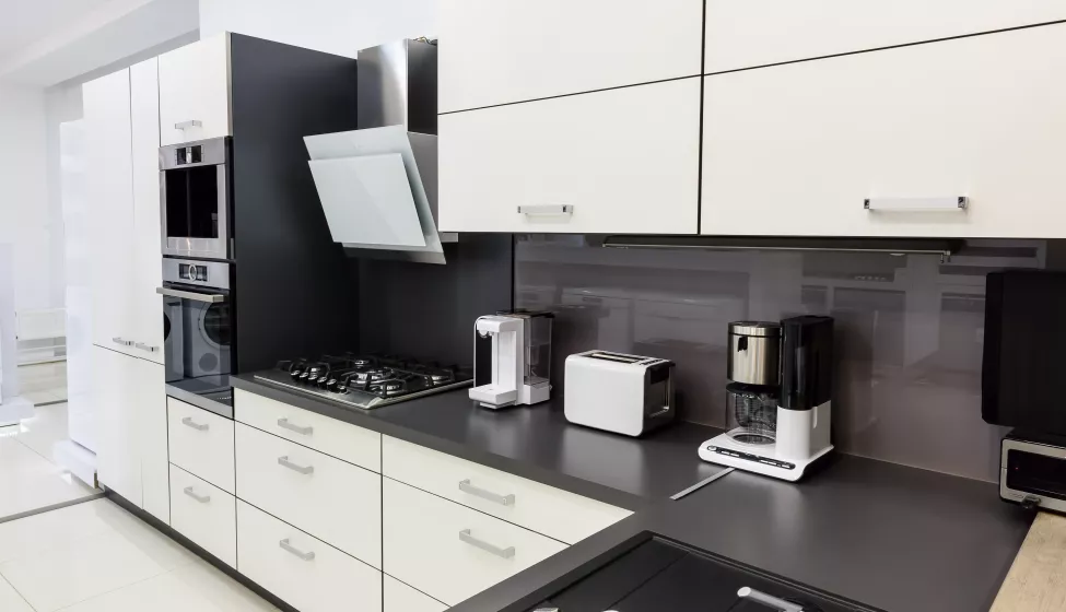 A modern hi-tech kitchen with white cabinets and black countertops