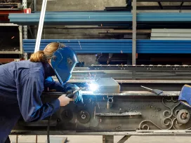 Welder working on steel beams. Exponent provides product process advisory for all types of materials.