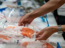 A man picks up a salmon fillet in the supermarket