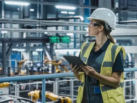Female Car Factory Engineer in High Visibility Vest Using Tablet Computer