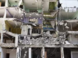 A collapsed apartment in the aftermath of an earthquake, rooms are exposed to the outside. Exponent experts assess the damage.