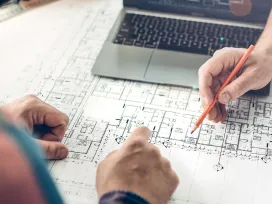 Two people examine construction blueprints while holding pencils. Exponent technical construction consulting. 